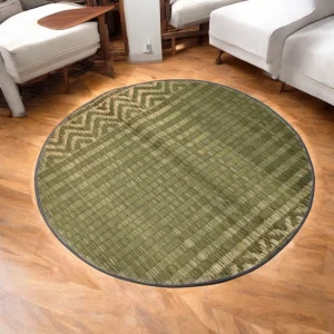 3ft round reed carpet mat with traditional green and beige woven pattern placed in a cozy living room with wooden flooring.