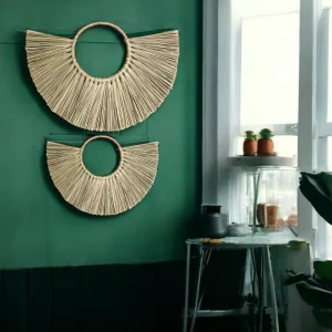 Two handmade half-moon wall hangings made from natural grass, displayed on a green wall in a modern boho room with natural light.