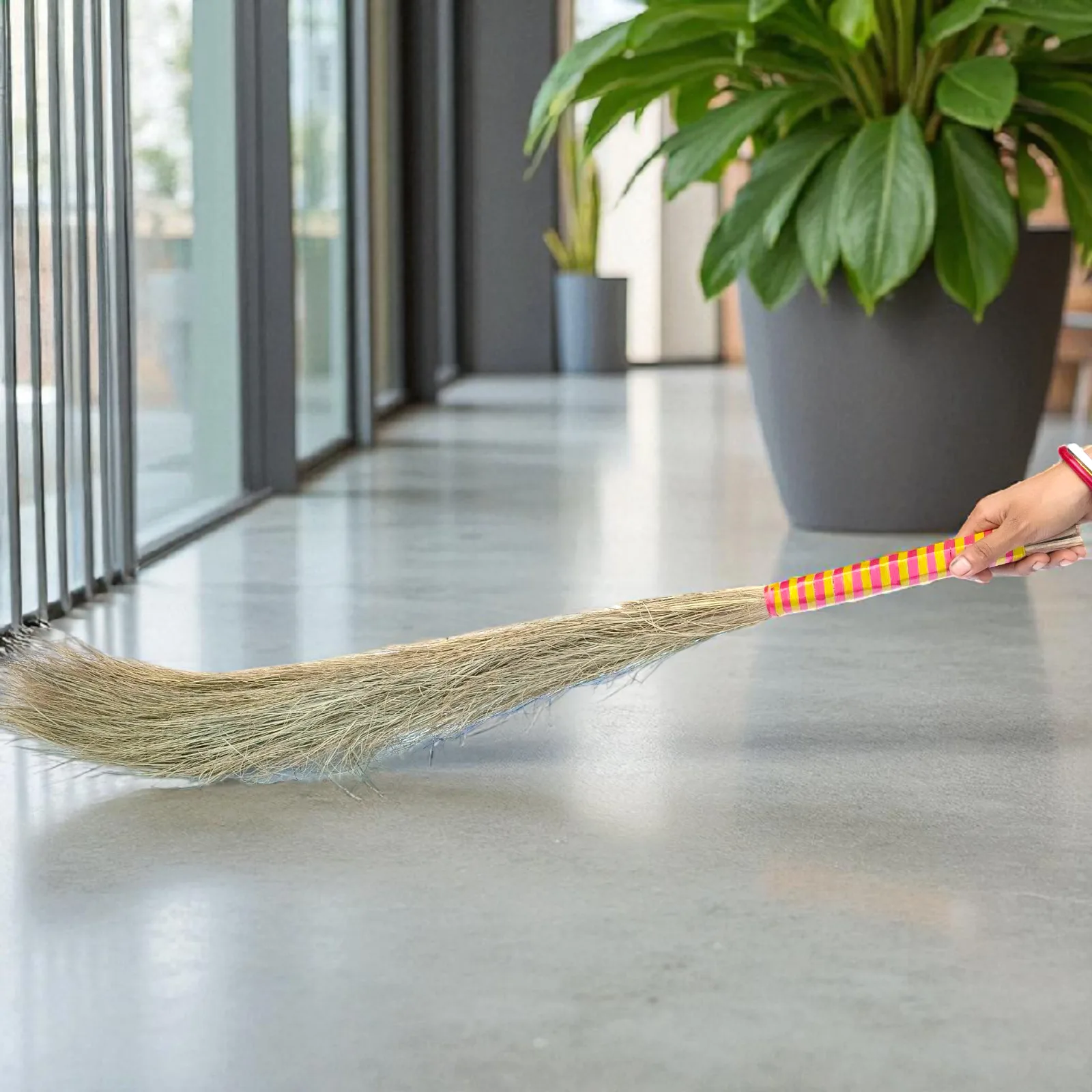 Handmade natural palm and coconut broom being used to sweep a clean indoor floor, eco-friendly cleaning tool.