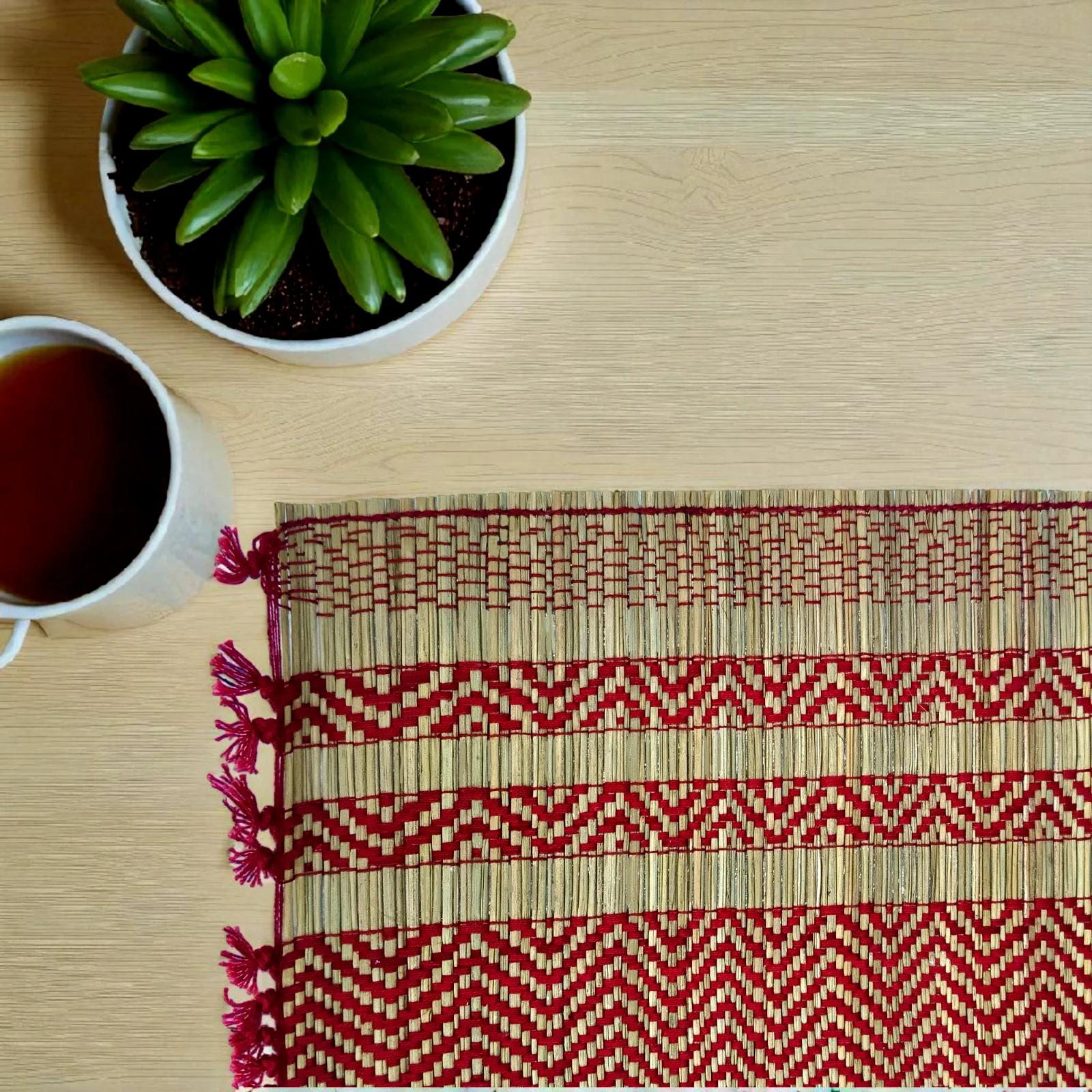 Handmade reed grass (madurkathi) table mat with red yarn design – eco-friendly dining table accessory.