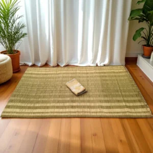Handwoven natural reed grass mat placed on wooden floor with white curtains and indoor plants – eco-friendly yoga and meditation mat made in India